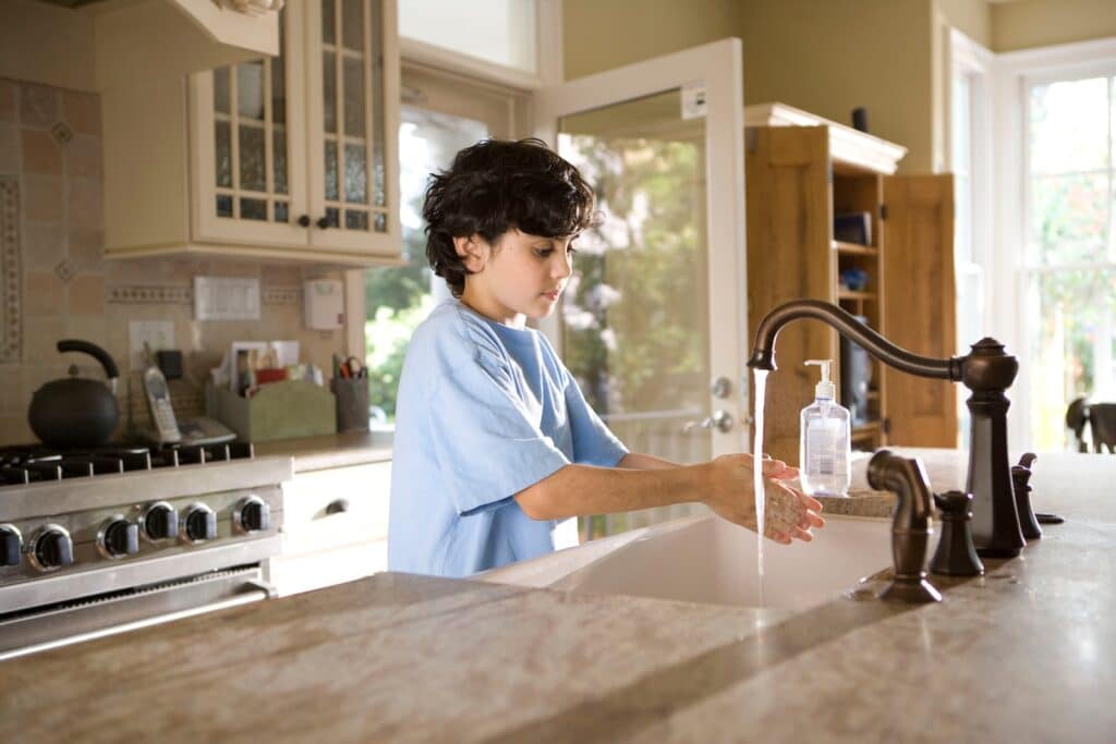 Environmental Stewardship: boy in blue polo shirt standing in front of sink