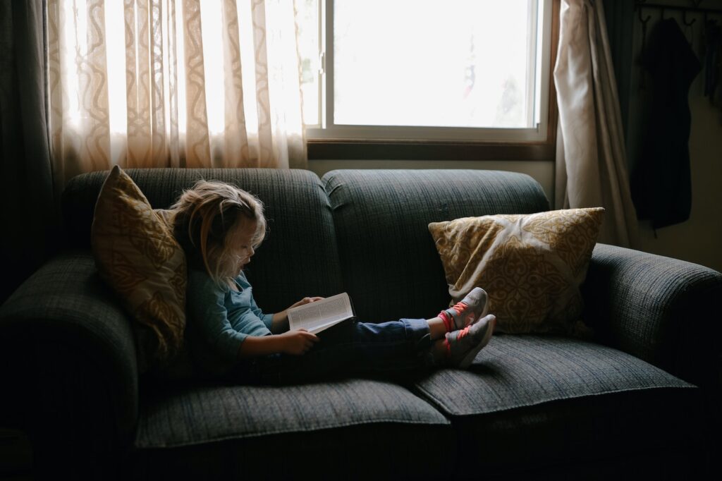 girl reading the Bible sitting on sofa