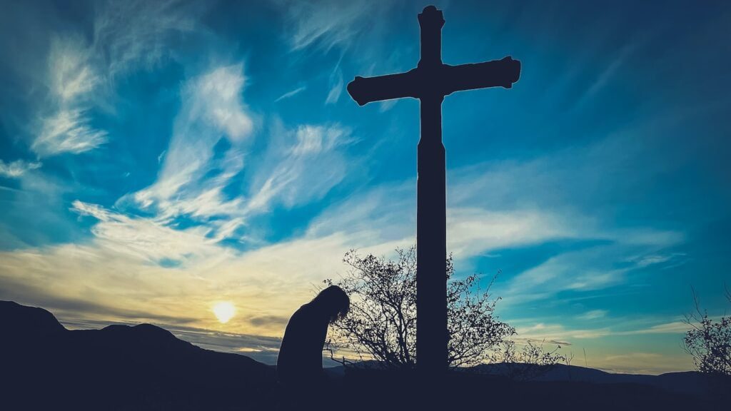 repentance: a person kneeling down in front of a cross