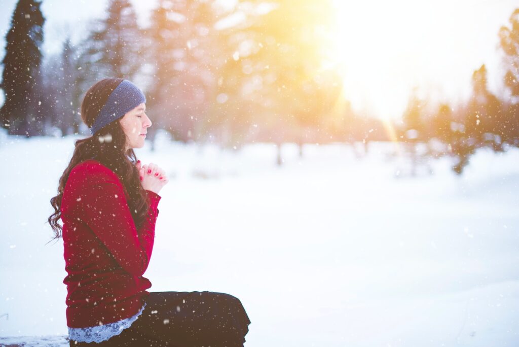 woman sitting with closed eyes surrounded by snow - know doubt embracing uncertainty in your faith