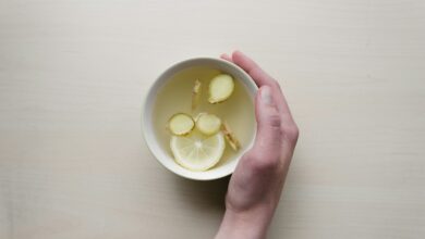 person holding white bowl with sliced lime and ginger inside - living by godly principles in your health
