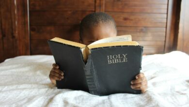 boy reading Holy Bible while lying on bed - overcome the 10 obstacles to hearing god's voice